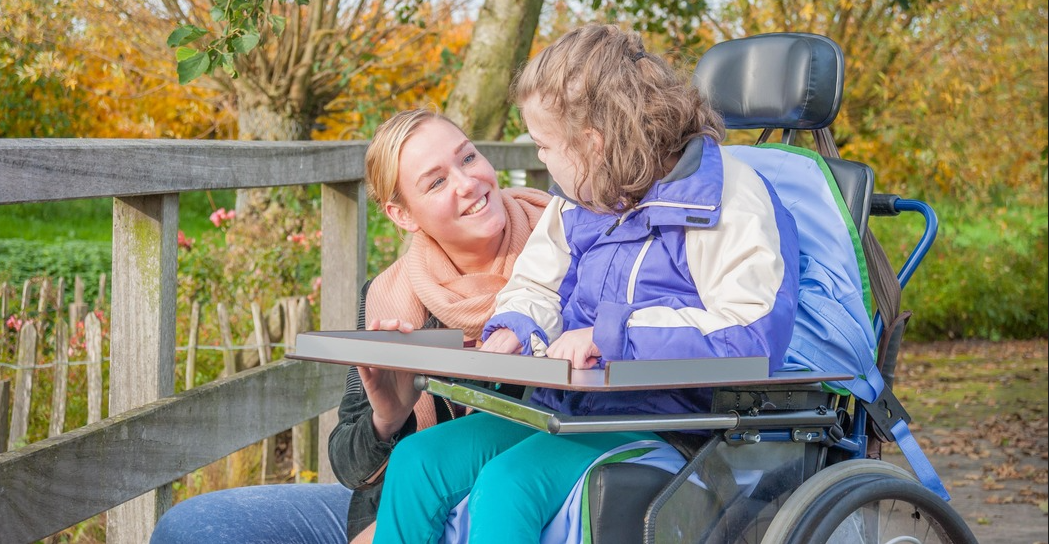 young girl with disability and support worker  outside